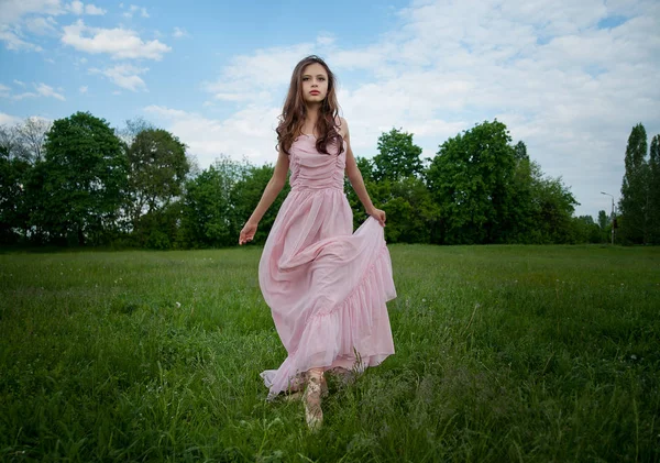 Dívka zvedla ruku dlouhé růžové šaty, šlápl do pointe, — Stock fotografie