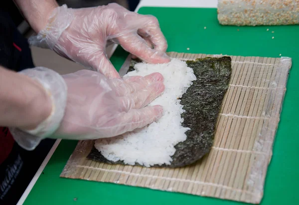 Em uma folha de Nori Sushi mestre desintegrando arroz, esfrega seu fi — Fotografia de Stock