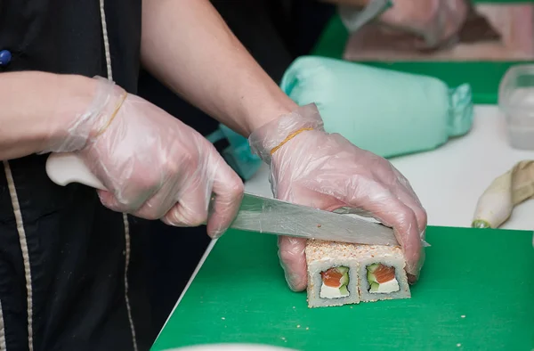 closeup hands Sushi master sushi knife which cuts the rolls into