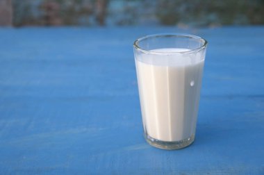 Sivri uçlu cam bardakta taze süt damlaları.