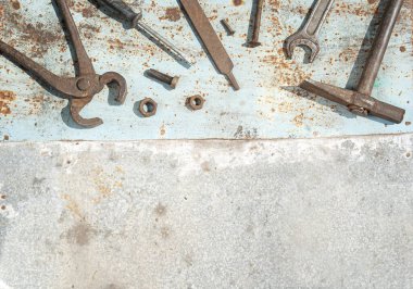 Eski paslı iş aletleri olan bir doku. Metalik arka plan lekelerinin üstünde anahtarlar, bir çekiç, bir tornavida, bir cıvata, bir somun, bir çivi, bir dosya, bir gaz anahtarı.