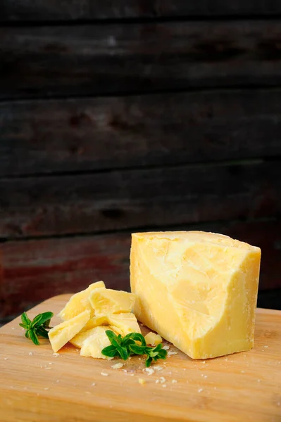 硬Parmesan奶酪被切碎 用薄荷糖装饰 在黑暗中躺在木板上 — 图库照片