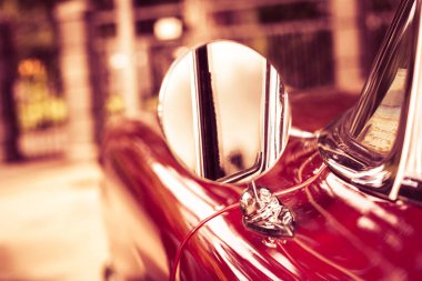 Bulanık bir arka plan üzerinde kırmızı retro araba. Detay: dikiz aynası. 