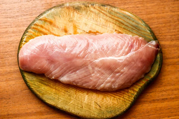 Filete de pollo crudo sobre tabla de madera sobre mesa — Foto de Stock