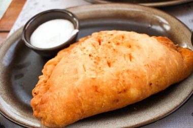 Kahverengi plaka üzerinde beyaz Sarımsak soslu fırında Cheburek hamur tatlısı