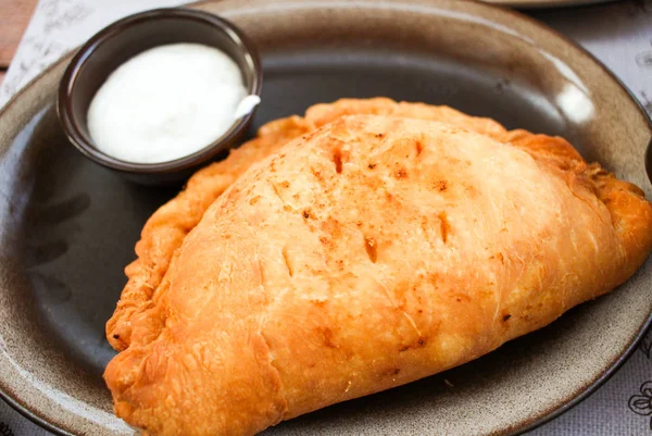 Kahverengi plaka üzerinde beyaz Sarımsak soslu fırında Cheburek hamur tatlısı