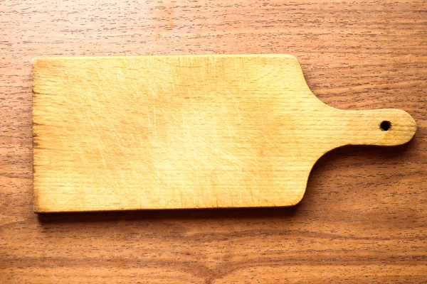 Tabla de cortar simple en la cocina sobre fondo de madera con em — Foto de Stock