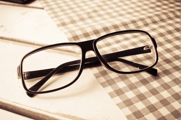 Черный глаз очки на белом деревянном столе с серой и белой сеткой — стоковое фото