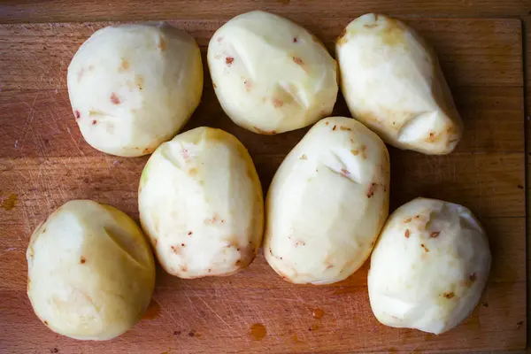 Peeled potatoes on wooden board close up detail. Preparing food — Stock Photo, Image