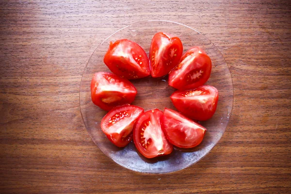 Round circle of cut tomatoes close up on a glass plate on wooden