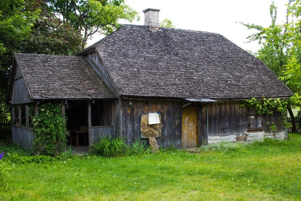 Old wooden countryside house with wooden roof with green grass g