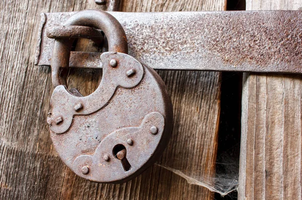 Old rusty padlock and spiderweb on wooden background, old myster — Stock Photo, Image