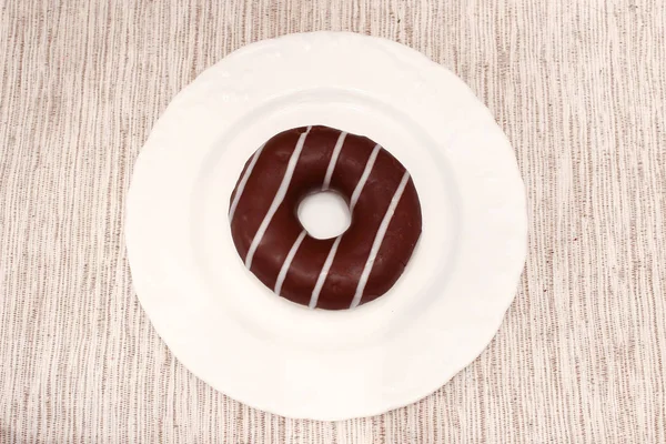 Brown stripped donut on plate on grey fabric background — Stock Photo, Image