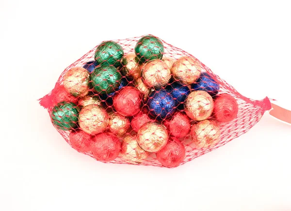 Colorful round chocolate candies in red net sack isolated on whi Stock Picture