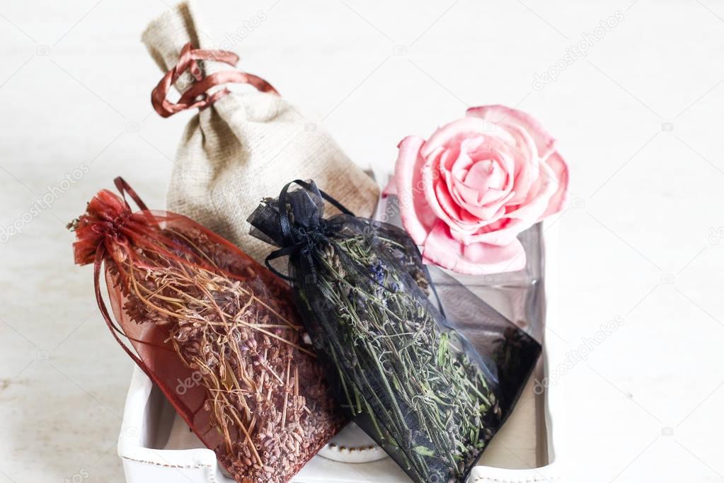 Dried scented herbs in red decorative bag and rose in porcelain 