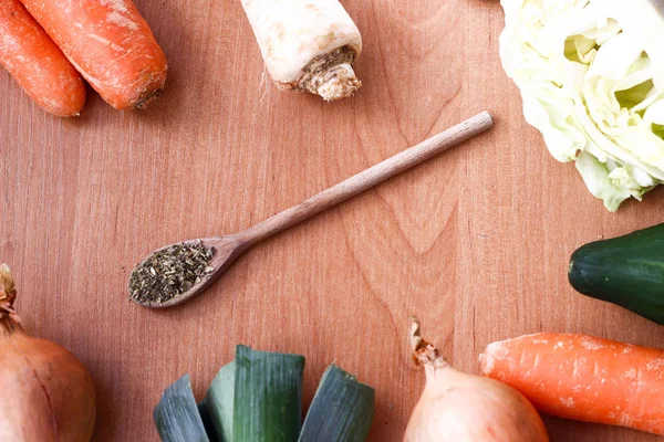 Composición de una cuchara de madera con especias verdes y verduras — Foto de Stock