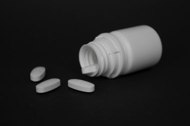 İlaç şişesi üzerinde farklı hapları ile siyah artalanları