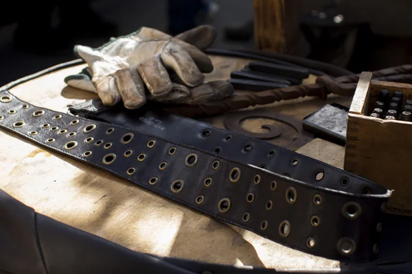 blacksmith working gloves and belt with different instruments on the table