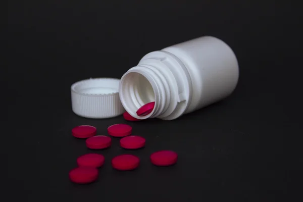 Medicine bottle on black backround with different pills — Stock Photo, Image