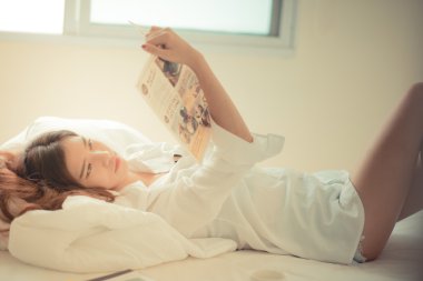 esmer kadın yatakta bir gazete okuyor 