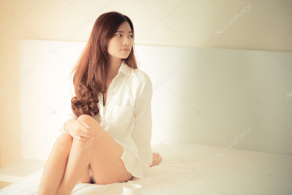 Elegant beautiful woman wearing white shirt posing in bedroom, 