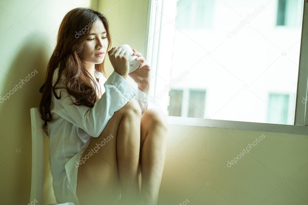 Beautiful brunette woman drinking and morning coffee in bedroom 