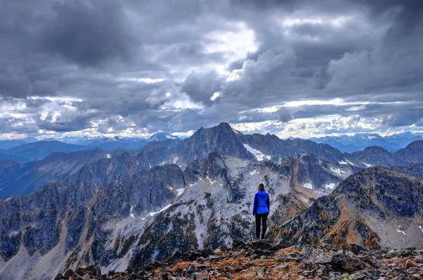 Vrouw op de bergtop onder storm wolken. — Stockfoto