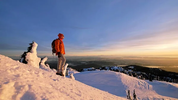 Hombre raquetas de nieve en la cima de la montaña viendo atardecer . — Foto de Stock