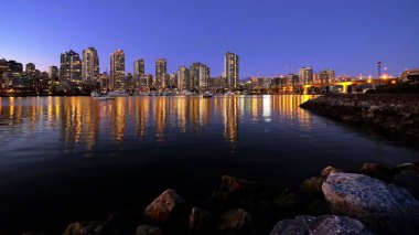 Gece şehir ışıkları yansımaları sakin suda.