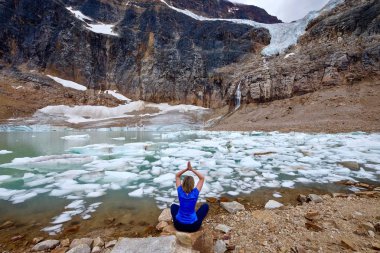 Kadın Yoga poz buzultaş Gölü meditasyon tarafından. Dağlar ve buzul. Göl icebergs ile. 