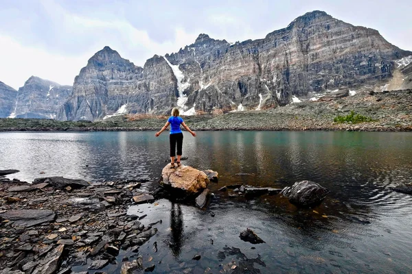 Blonde vrouw door alpine meer genieten van het uitzicht op de bergen op een regenachtige dag. — Stockfoto