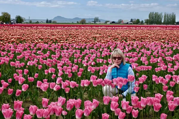Schöne blonde Frau in bunten Tulpenfeldern. — Stockfoto