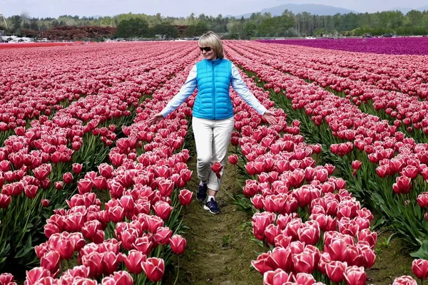 Glücklich lächelnde Frau geht durch bunte Tulpenfelder. — Stockfoto