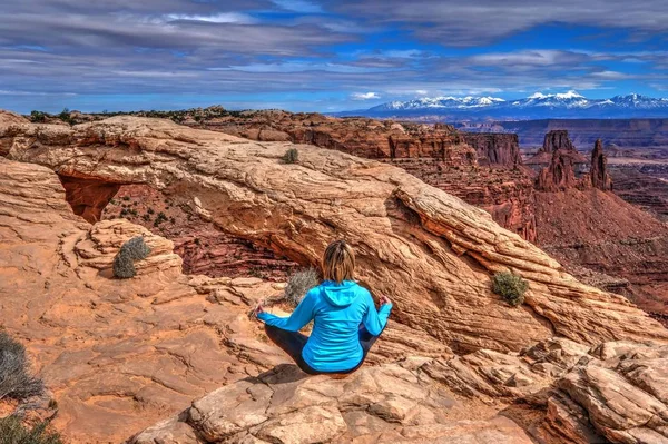 Mujer joven meditando en el acantilado por Mesa Arch . — Foto de Stock