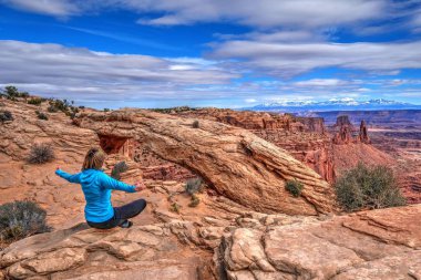 Genç kadını uçurum Mesa Arch tarafından meditasyon.