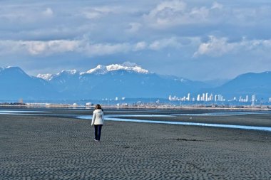 Vancouver şehir ve dağ manzaralı sahilde yürüyen kadın. 