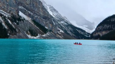 Canoeing in emerald Lake Louise by Victoria Glacier and Fairview Mountain.   clipart