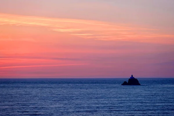 Faro sobre rocas al atardecer . — Foto de Stock