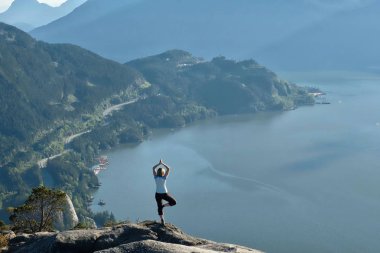 Dağ tepe okyanusa yukarıda üzerinde meditasyon kadın. 
