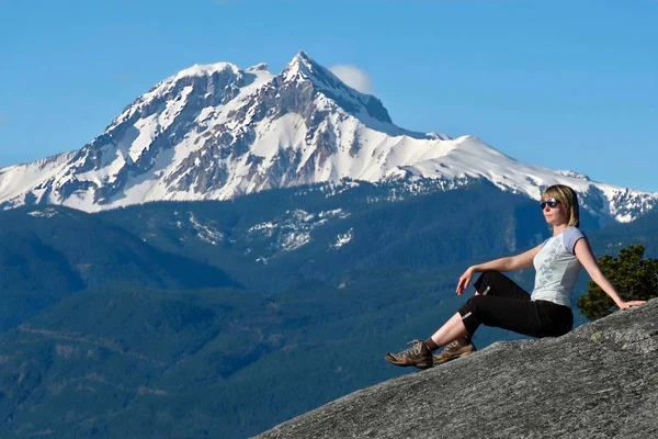 Viaje a Canadá. Mujer en acantilado de montaña contra pico nevado — Foto de Stock