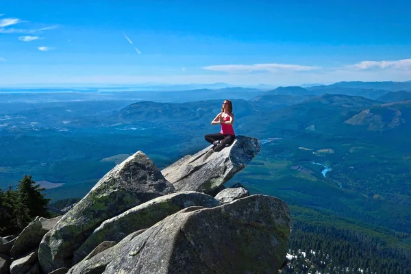 Jonge vrouw mediteren op rots boven prachtige vallei. — Stockfoto