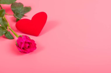 Pembe arka planda kırmızı kalbi olan pembe bir gül