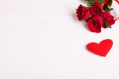 Red rose bouquet, heart on white wood background