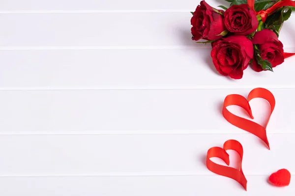 Red rose bouquet, heart ribbon on white wood background Stock Photo
