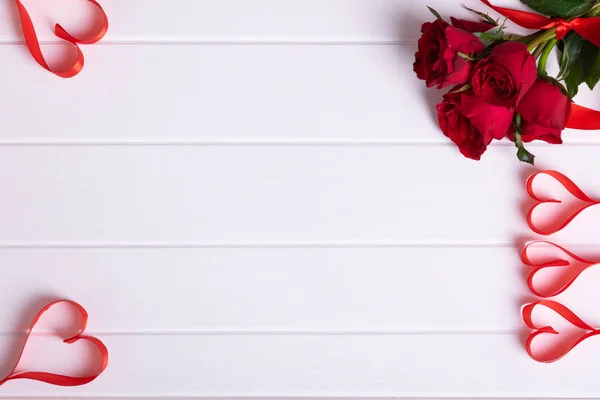 Red rose bouquet, heart ribbon on white wood background Stock Picture