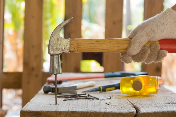 Çekiç, çekiç ve çekiç tutan eldiven ile çivi yapıldı.