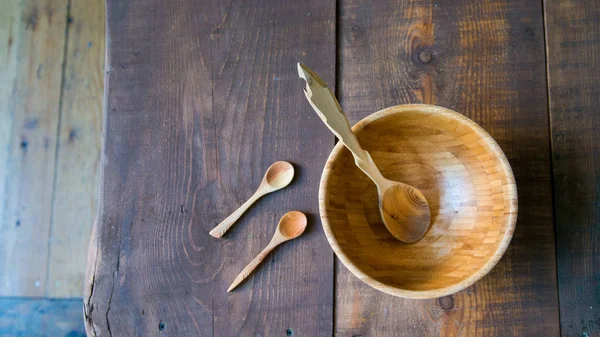 Empty wooden bowl and spoons on wooden background