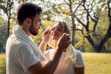 Genç çiftler egzersiz yaptıktan sonra ter siliyorlar..