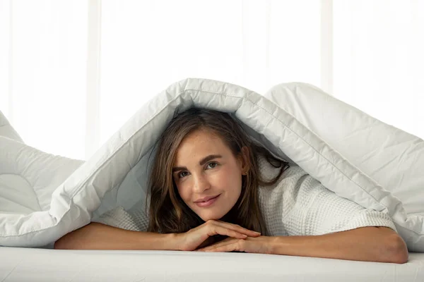 Piękna kobieta pod białym kocem na łóżku. — Zdjęcie stockowe
