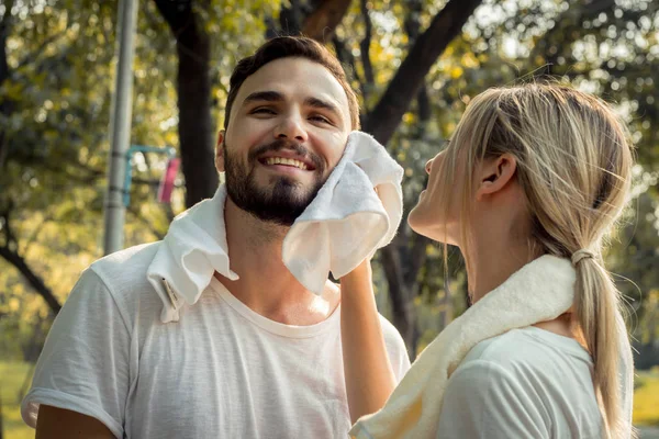 Mujer joven limpió el sudor para el novio después de hacer ejercicio . —  Fotos de Stock